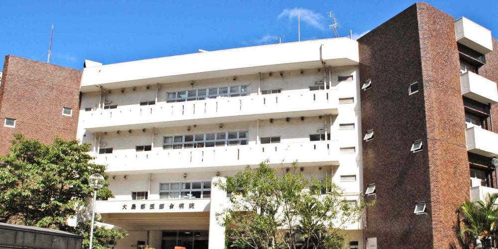 赤レンガと白い外壁の介護施設の建物外観。複数階建てで窓が規則的に配置されている。
