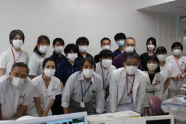 マスクを着用した介護職員や医療スタッフの集合写真。施設内の会議室と思われる空間での撮影