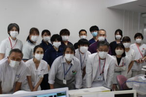 介護施設のスタッフ団体写真。多数の職員がマスク着用で集合している様子。